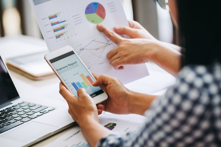 Two people reviewing business reports with charts illustrating performance